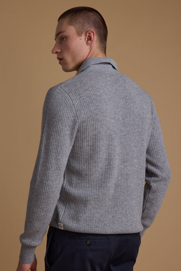 A person with short hair is shown from behind, wearing the Barkers Braxton Merino Long Sleeve Polo in light gray and dark navy pants, standing against a plain beige background.