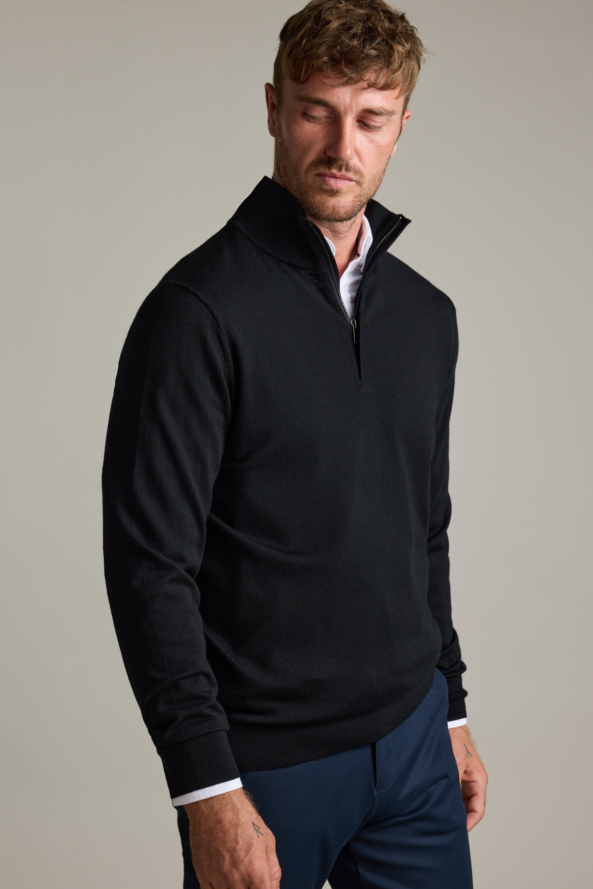 Man in Barkers Skyland ZQRX Merino 1/4 Zip and navy pants, looking down neutrally.