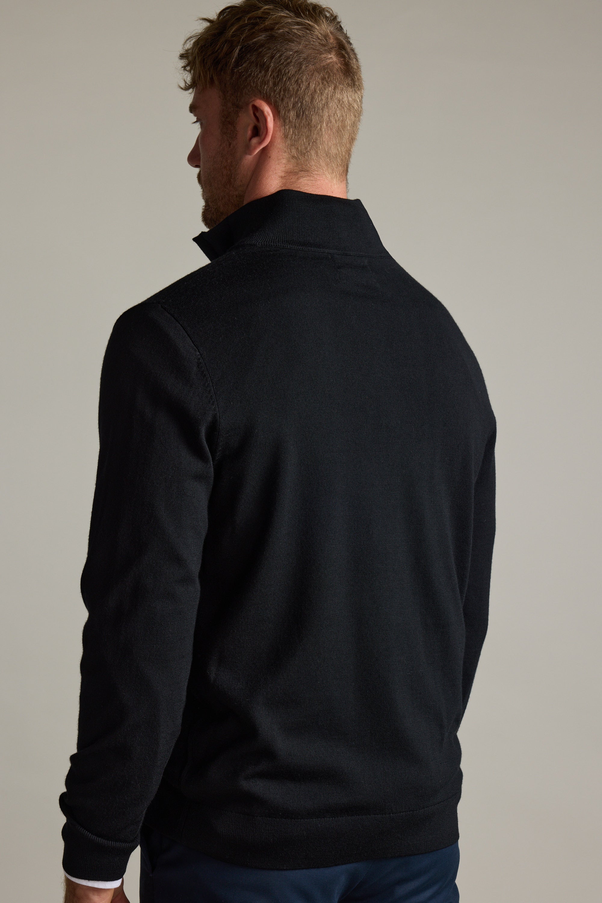 Man with short hair wears a Barkers Skyland ZQRX Merino 1/4 Zip, facing away from the camera.