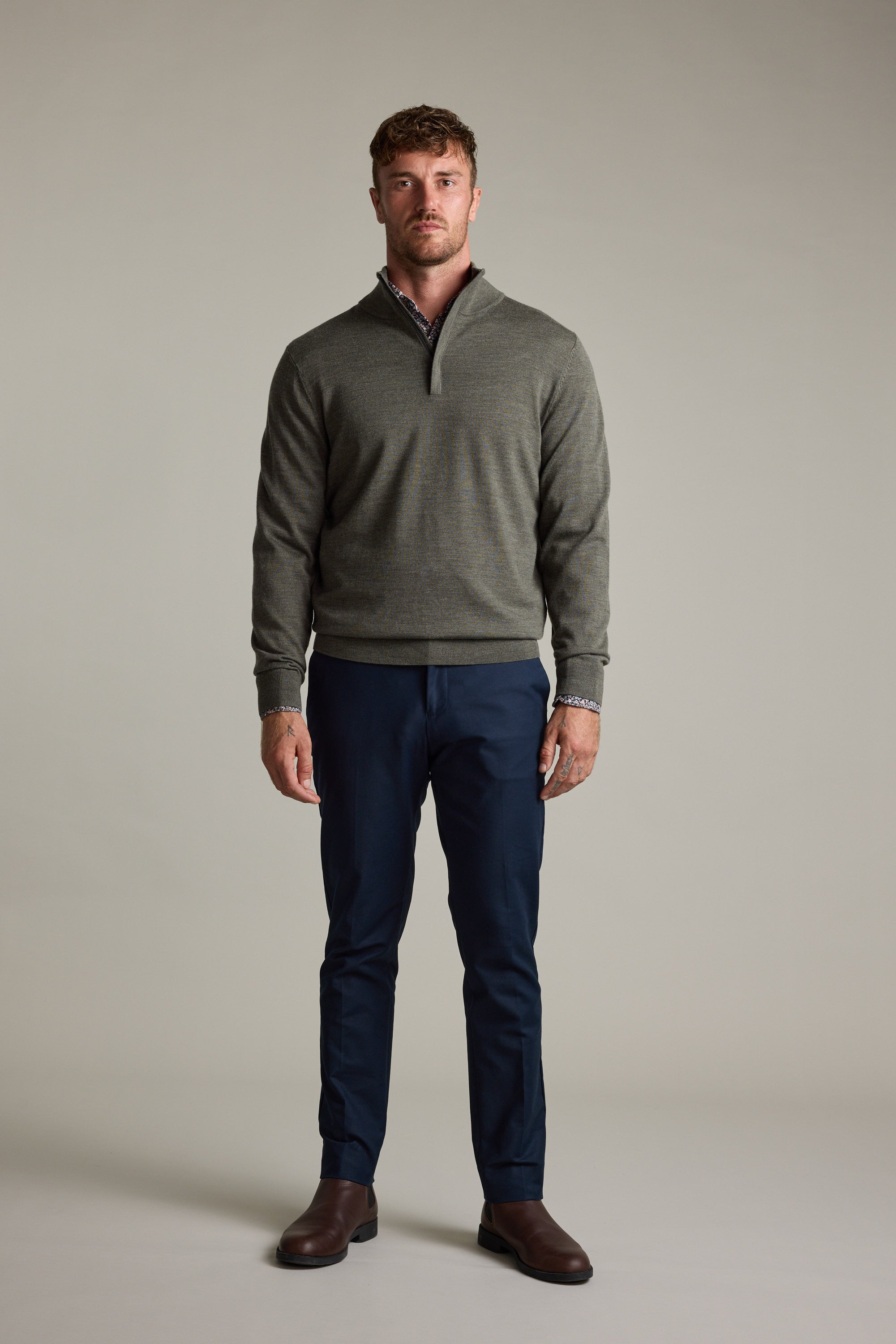 Man wears a gray Barkers Skyland ZQRX Merino 1/4 Zip, navy pants, and brown shoes.