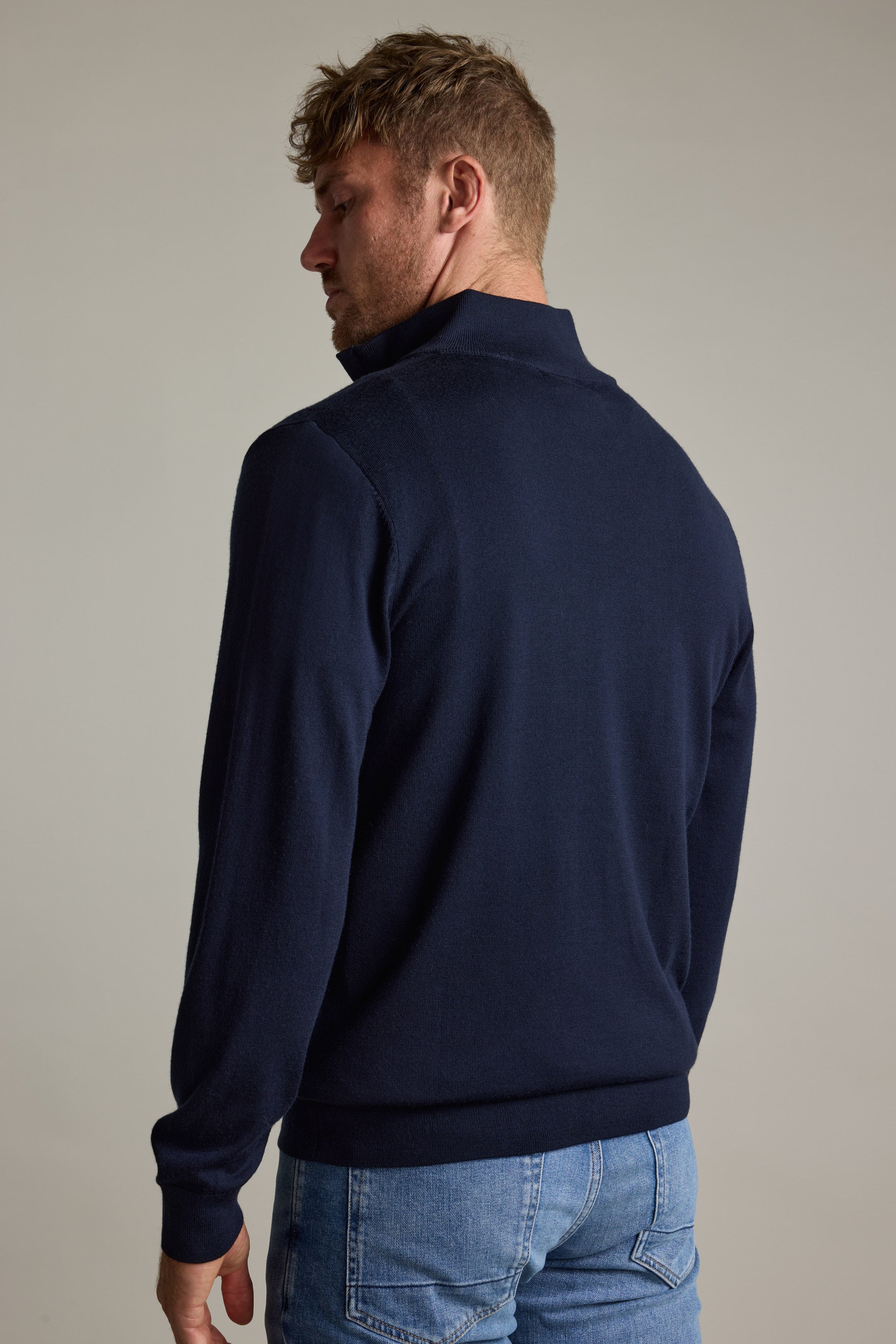 Man in a Barkers Skyland ZQRX Merino 1/4 Zip and blue jeans, facing away.