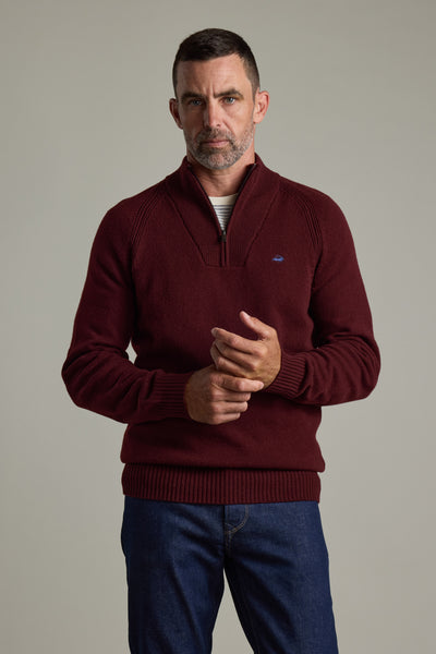 Man wears Barkers Rowley Woollen 1/4 Zip sweater and blue jeans against a light gray background.