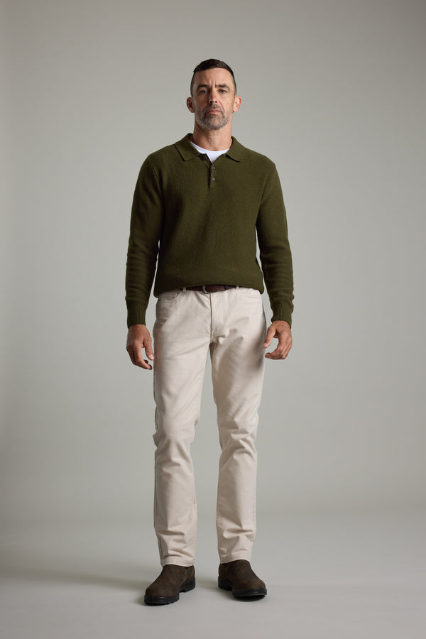 Man in studio wears Barkers Ainsley Woollen Long Sleeve Polo, beige pants, and brown shoes.