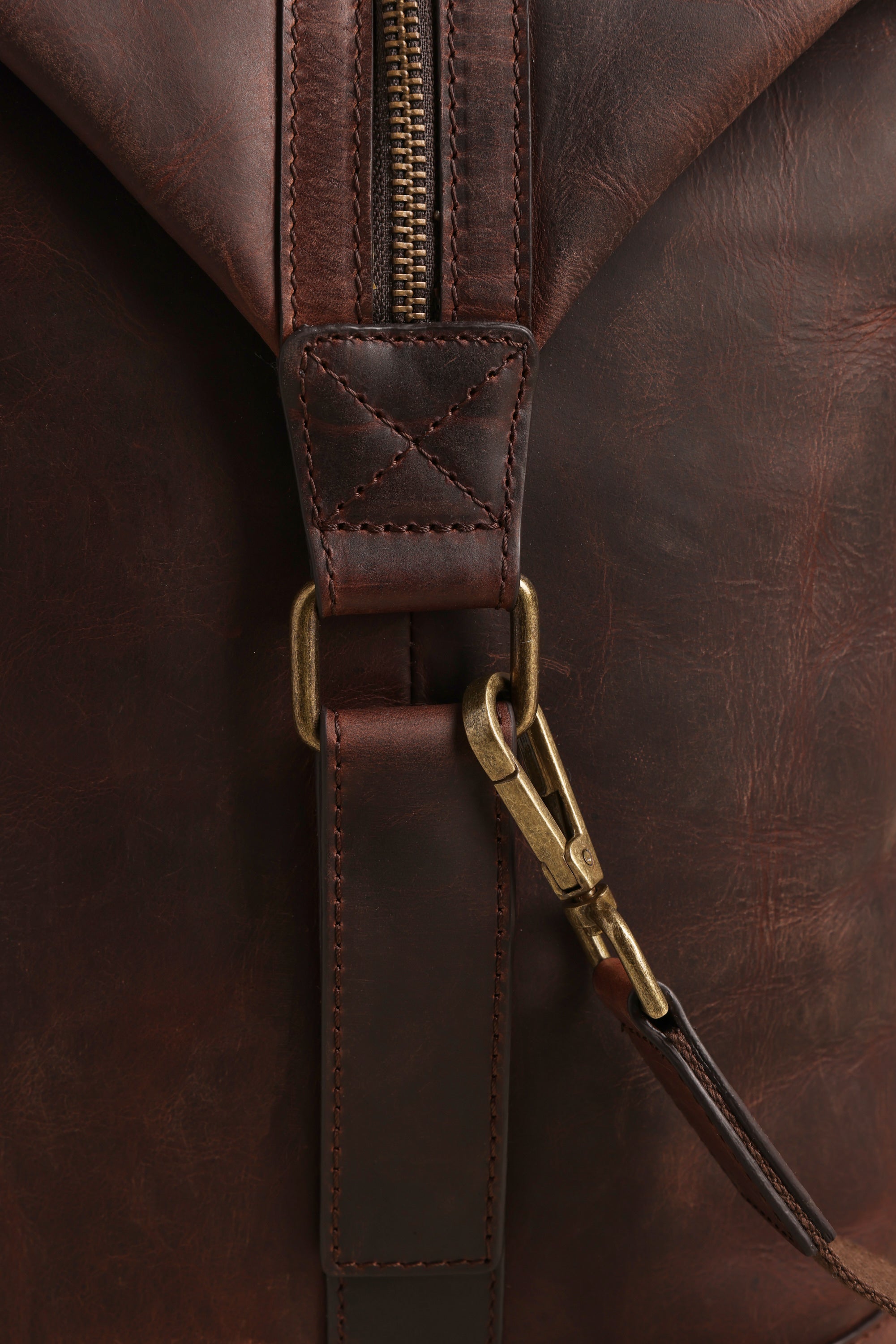 Close-up of the Barkers Costello Leather Weekender shows its rich, textured brown leather, brass clasp on a stitched strap, and visible zipper, highlighting the premium surface and careful craftsmanship.
