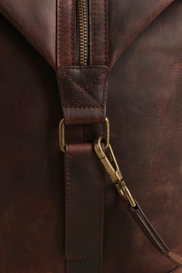 Close-up of the Barkers Costello Leather Weekender shows its rich, textured brown leather, brass clasp on a stitched strap, and visible zipper, highlighting the premium surface and careful craftsmanship.