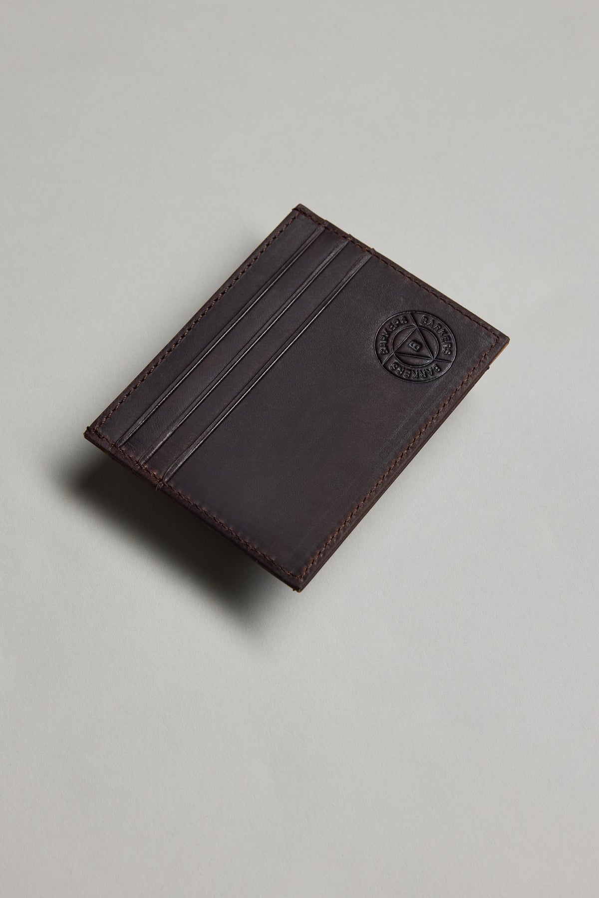 Barkers Taylor slim dark brown leather card wallet with logo, shown on a light gray surface.