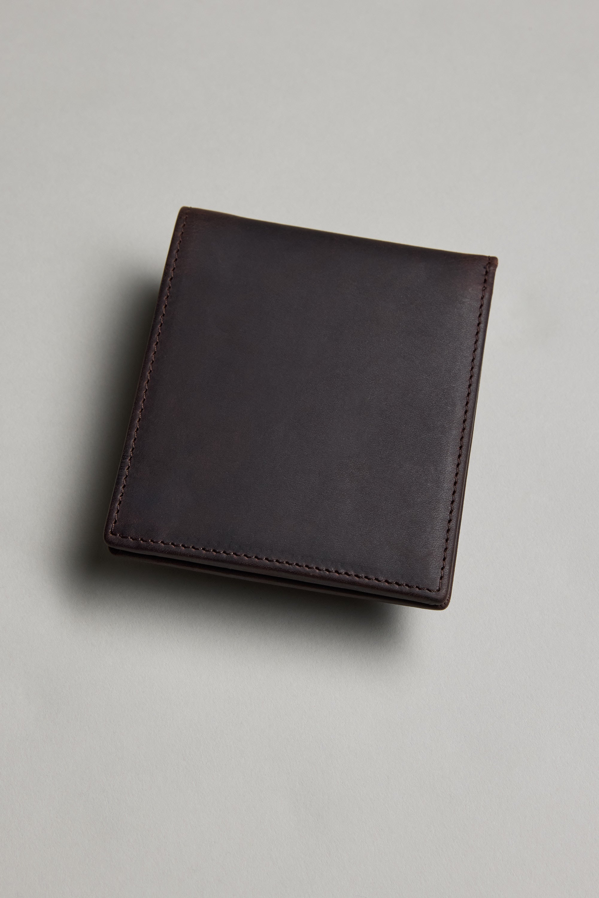 The Barkers Harris Leather Fold Wallet, a slim and neatly stitched dark brown wallet, rests on a light grey surface.
