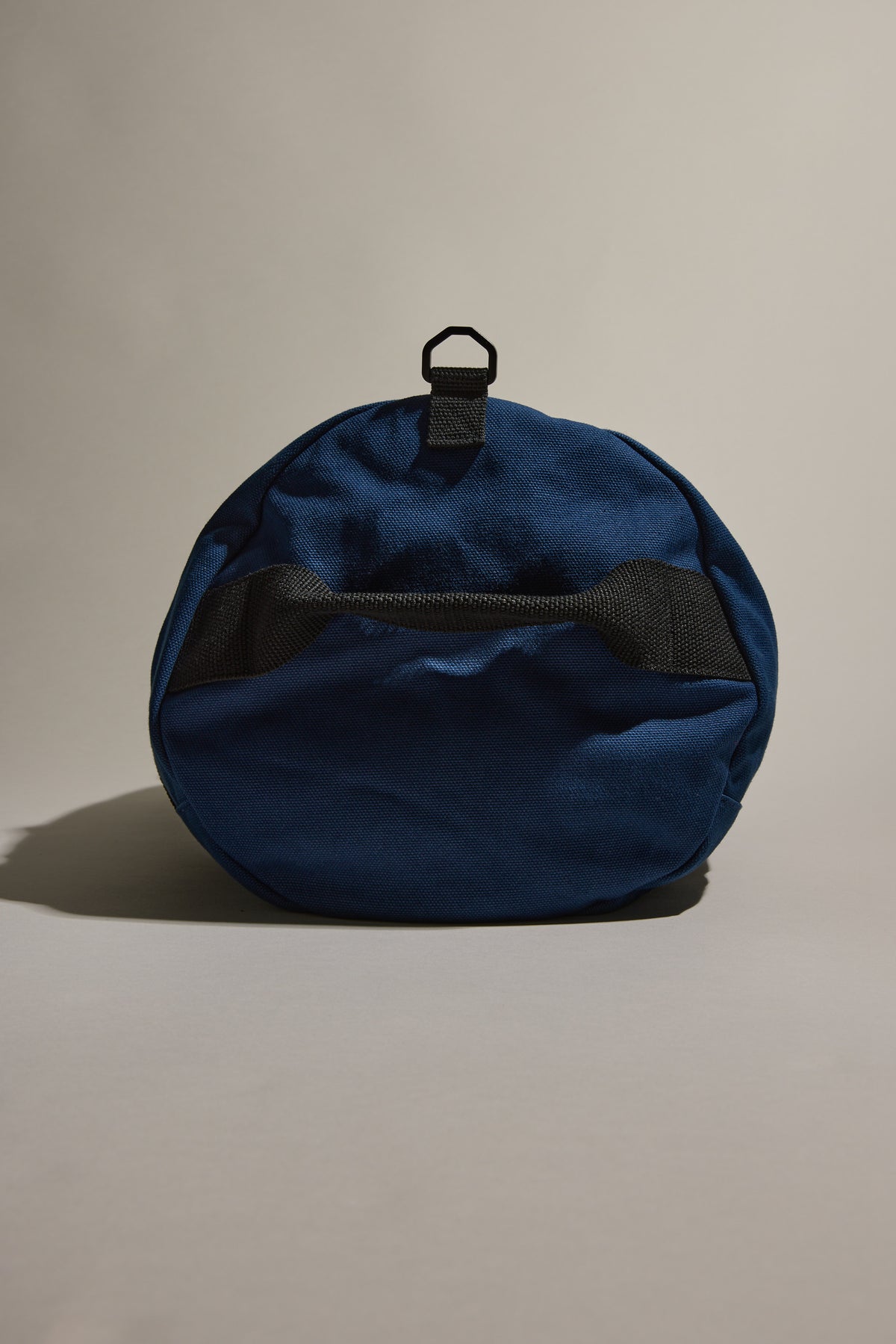 Blue Barkers Canvas Duffle Bag, round with black handle and pocket, upright style.