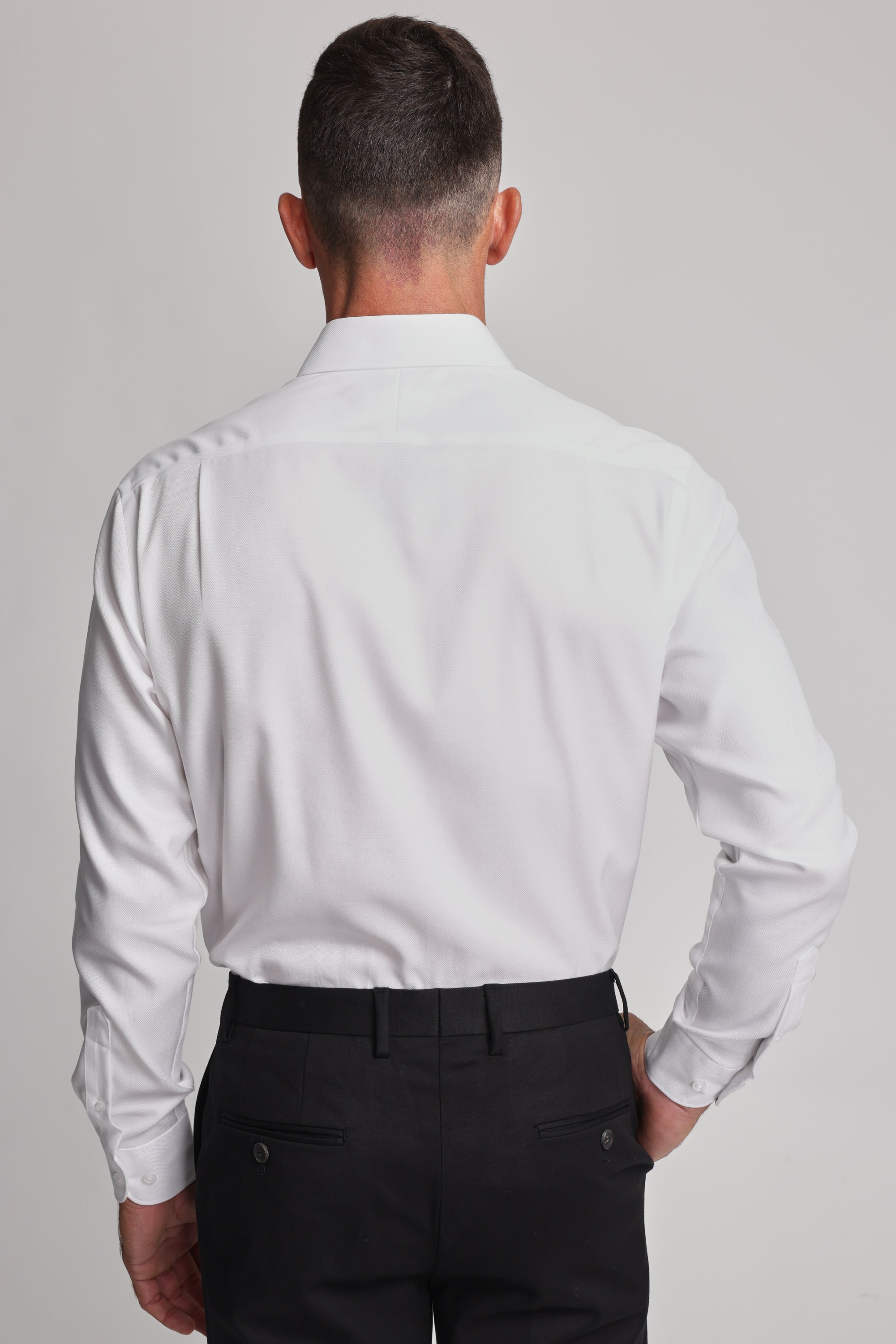 A man stands with his back to the camera, wearing the Barkers Mexted Texture Shirt in white and black dress pants, set against a plain light background.