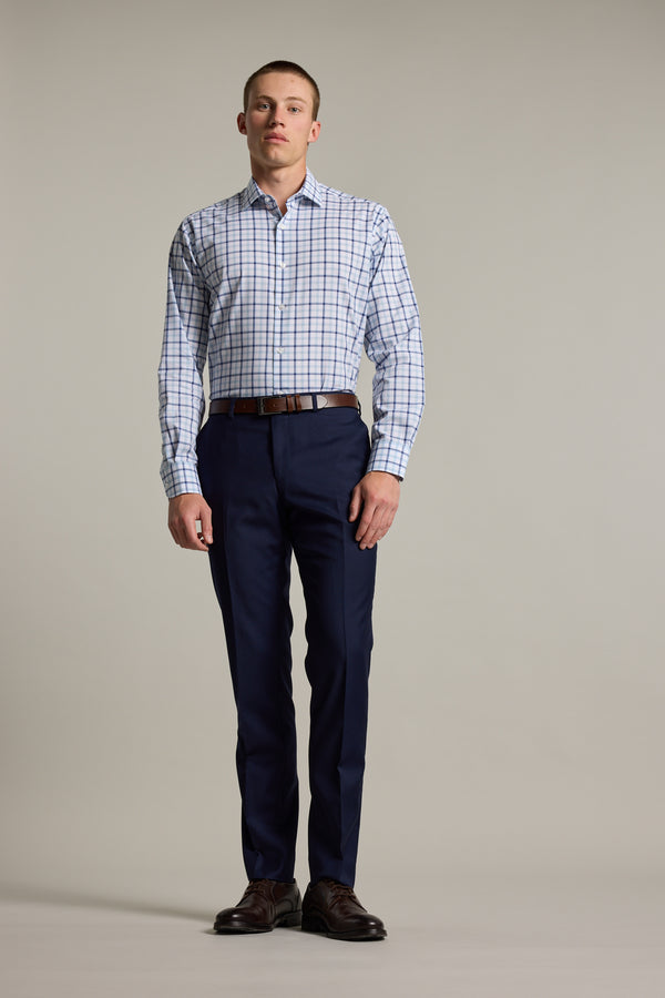 A man stands against a plain background wearing the Barkers Wesley Check Business Shirt paired with dark blue dress pants, a brown belt, and dark brown dress shoes.