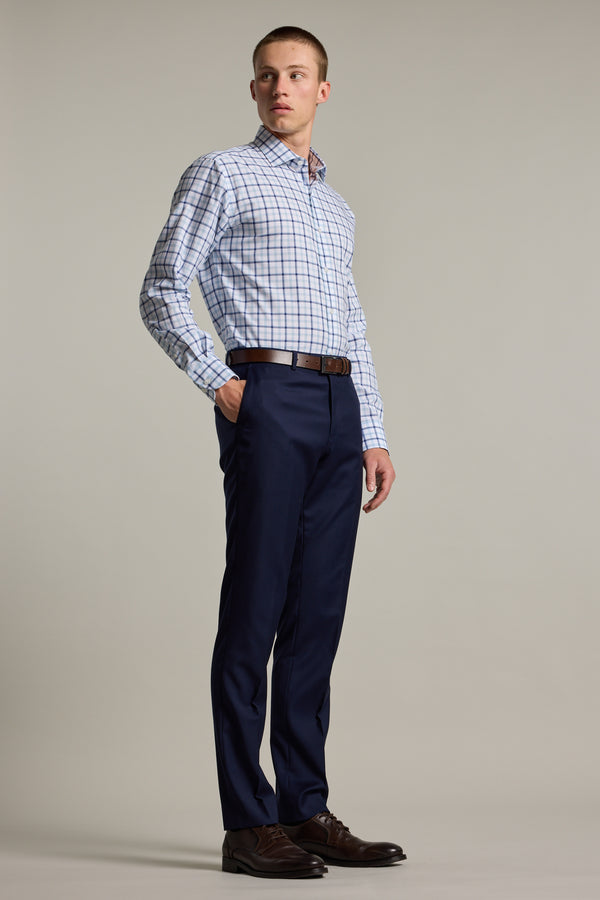 A man stands against a plain background wearing the Barkers Wesley Check Business Shirt. He pairs it with navy dress pants, a brown belt, and brown dress shoes, looking slightly to the side with a neutral expression.