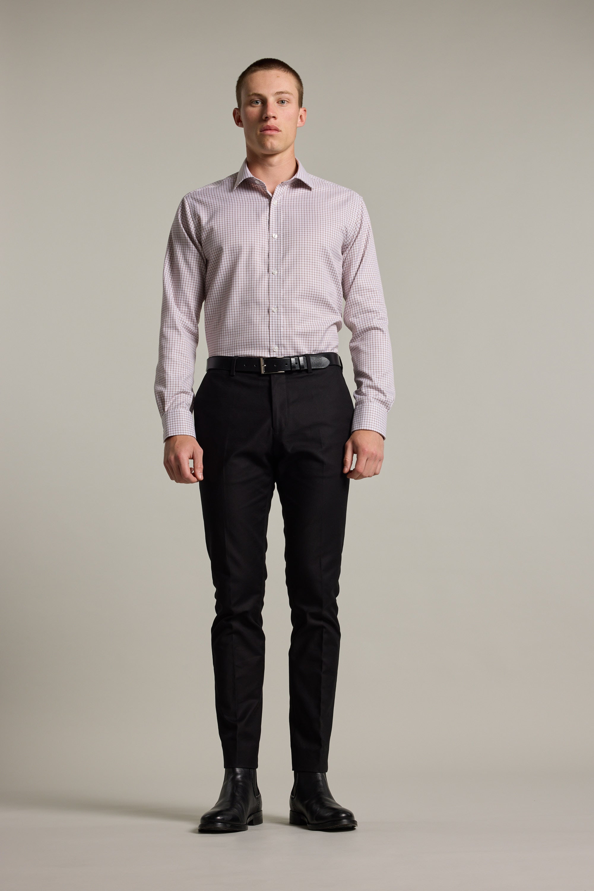 A man faces forward against a plain background, wearing the Barkers Marbury Check Business Shirt with a tailored fit, paired with black dress pants, a black belt, and black dress shoes.