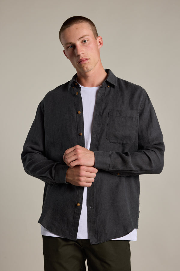 A person with short hair wears the Barkers Delano Linen Shirt in a classic fit over a white tee, standing against a plain background with hands loosely clasped and looking at the camera with a neutral expression.