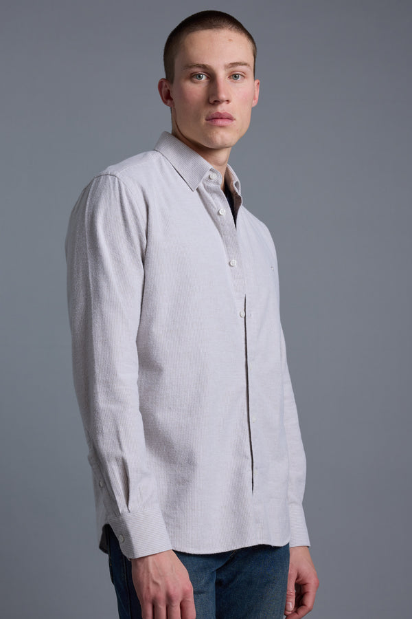 A young man with short hair wears the Barkers Maynard Oxford Stripe Shirt and blue jeans, standing against a plain gray background and looking slightly to the side with a neutral expression.