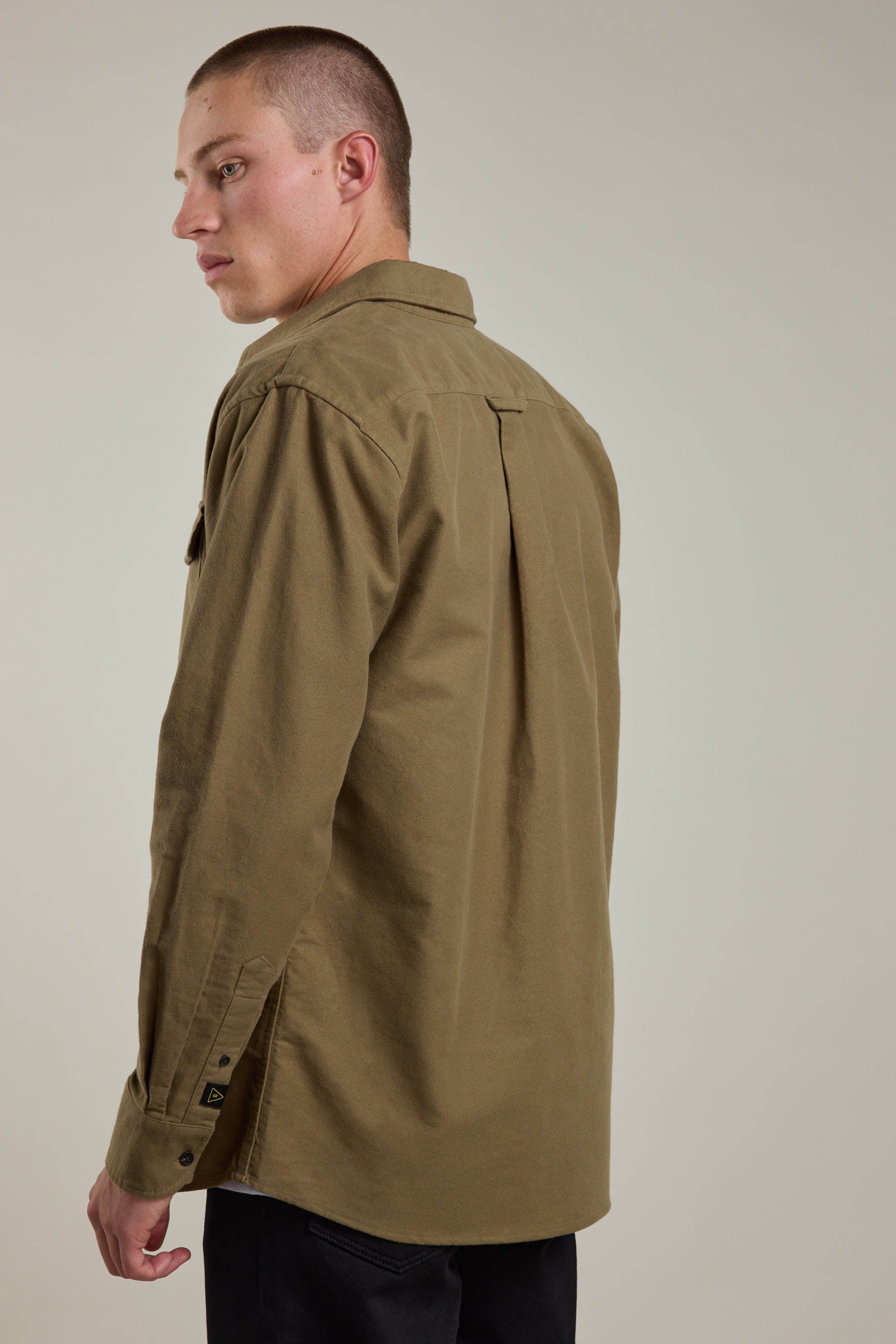 A person with short hair, shown from behind against a plain light background, wears the Barkers Tayler Moleskin Overshirt in light brown and looks over their shoulder.