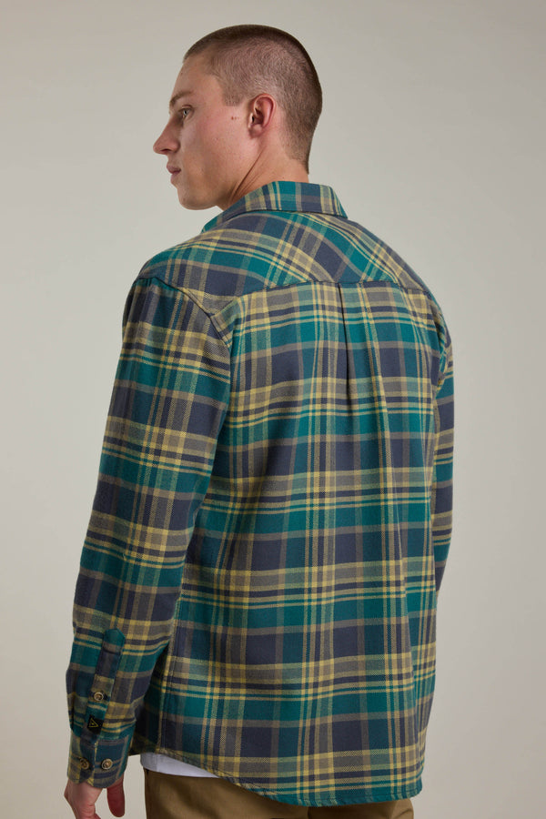 A man with short hair, seen from behind and looking left, wears the Barkers Wallis Check Overshirt in green, yellow, and blue—an essential addition to any men's wardrobe. He stands against a plain light background.