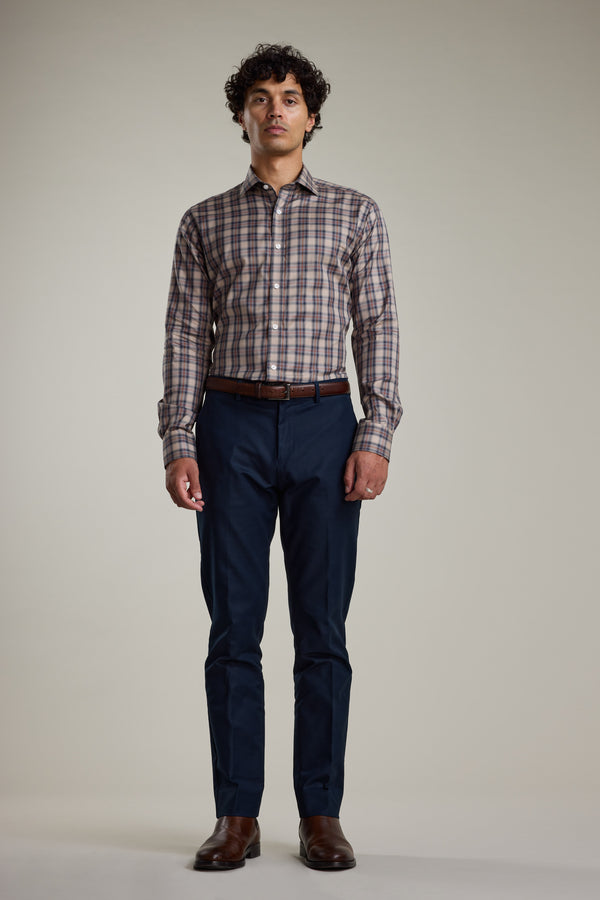 A man faces forward wearing the Barkers Norco Check Business Shirt, a tailored fit brown plaid button-up, paired with dark blue pants, a brown belt, and brown shoes against a plain light background.