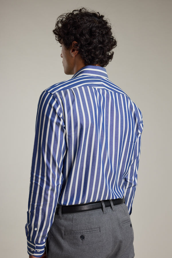 A man with curly dark hair is seen from behind wearing the Barkers Nandas Stripe Business Shirt, featuring blue and white vertical stripes, paired with gray trousers and a black belt against a plain light background.