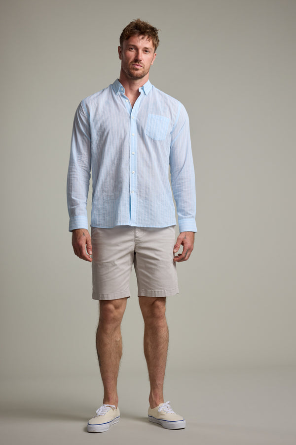 A man stands against a plain background wearing the Barkers Russell Stripe Shirt, a lightweight 100% cotton long sleeve, paired with khaki shorts and white sneakers. He faces forward with a neutral expression and his arms at his sides.
