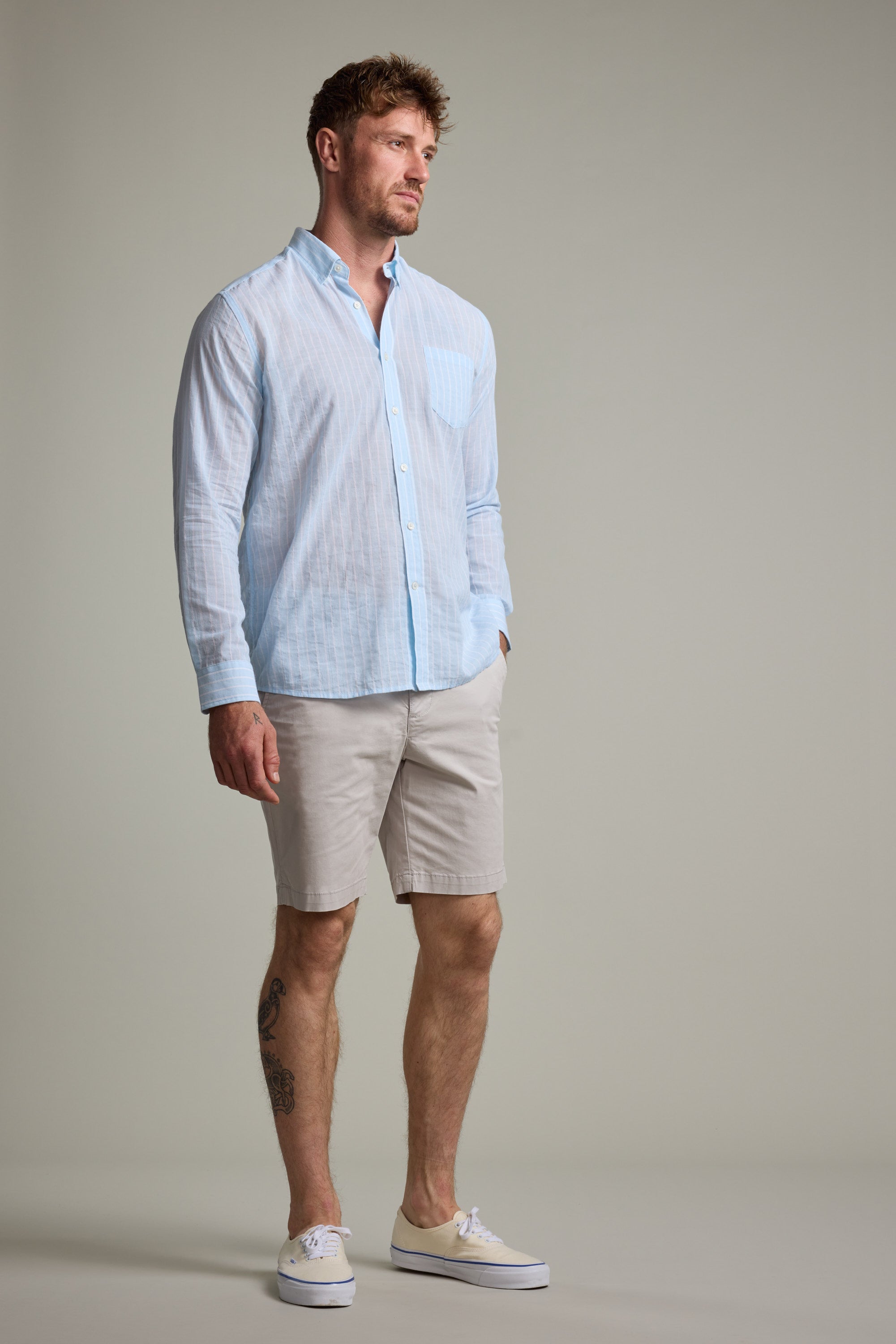 A man wears a Barkers Russell Stripe Shirt and shorts.