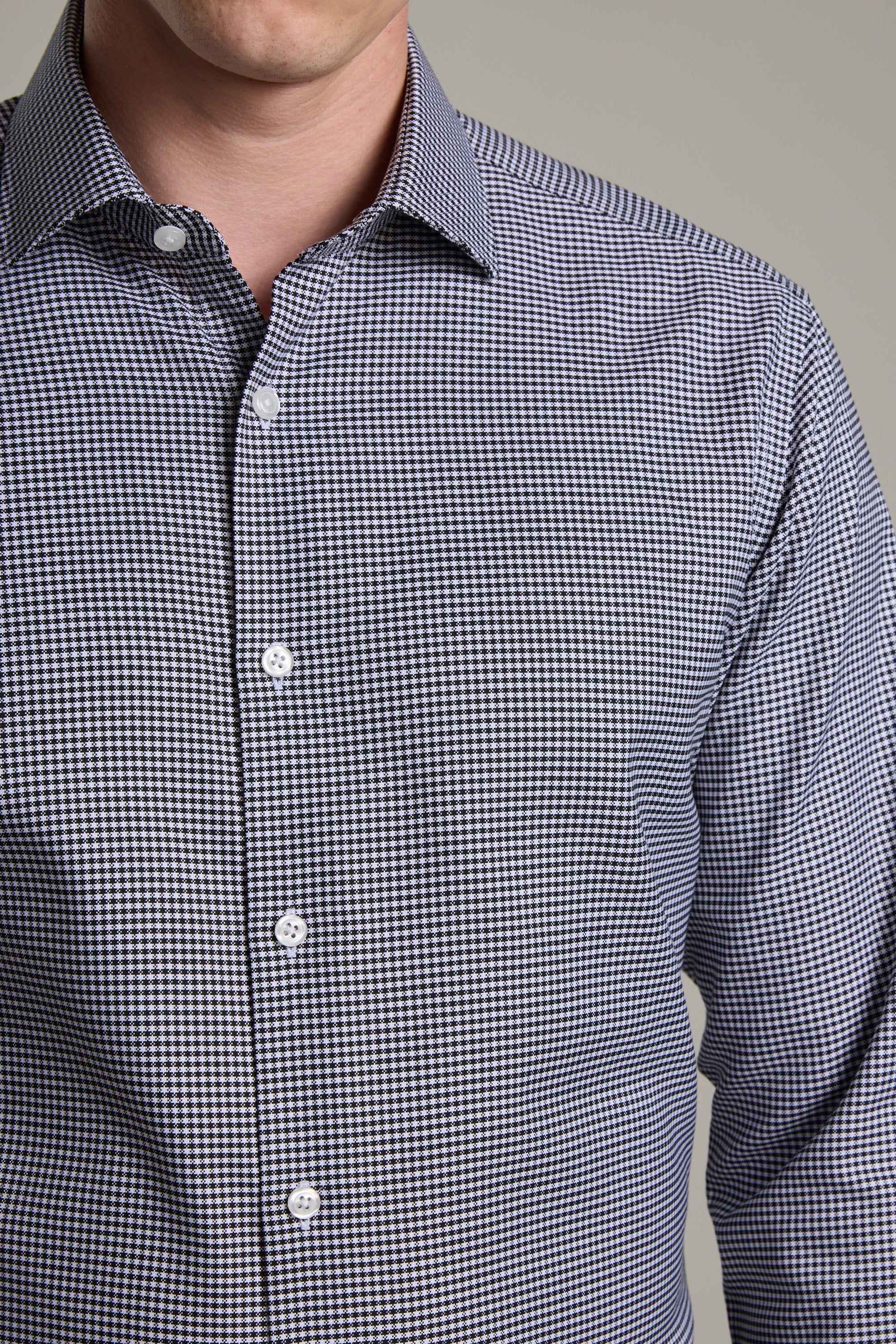 A man wears the Barkers Mitchel Check Business Shirt, a tailored fit, long-sleeve shirt featuring a small black and white check pattern, shown from shoulders to waist against a plain background.