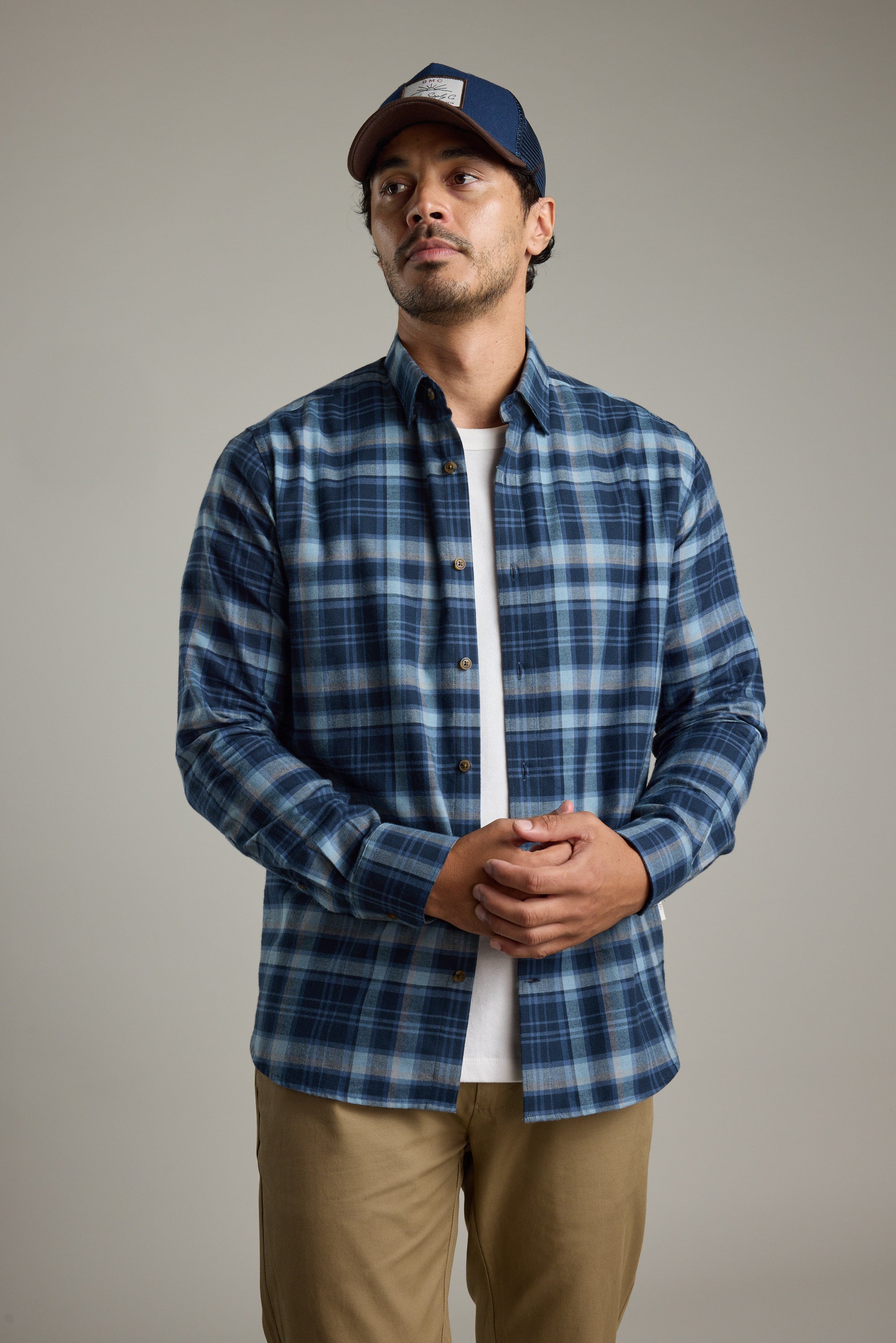 Man in a Barkers Lexington Check Shirt, tan pants, and navy cap against a plain background.