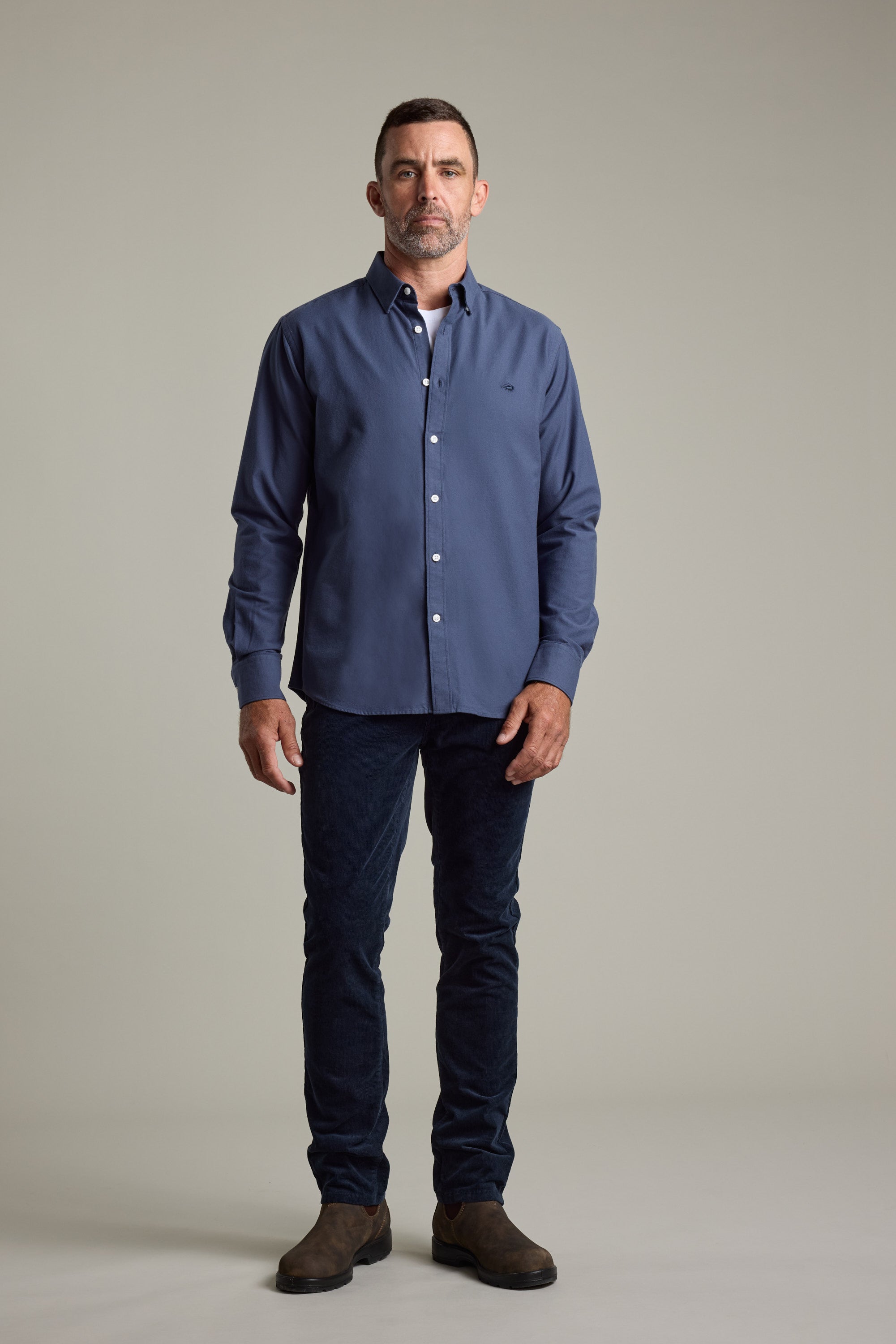 Man wears Barkers Maynard Oxford Shirt, dark pants, and brown shoes.