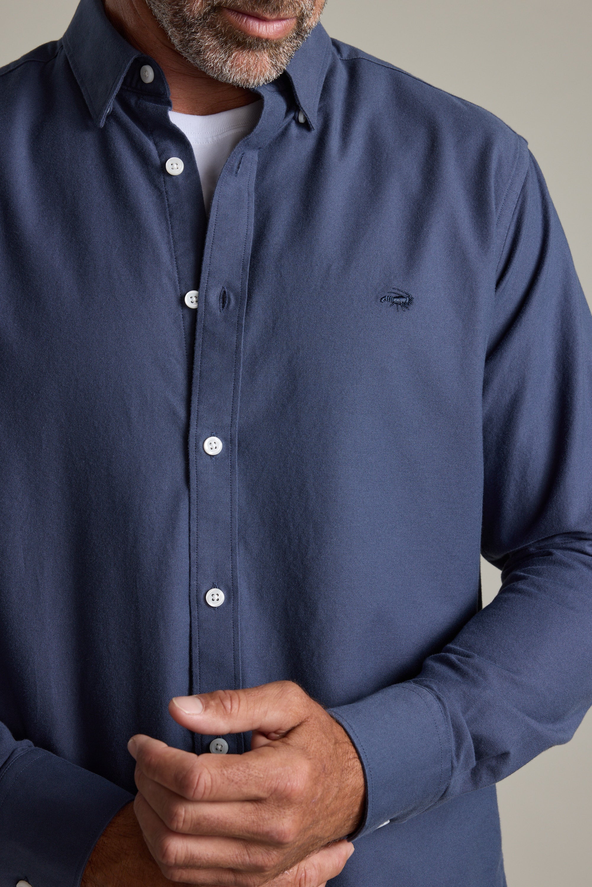 Man in a Barkers Maynard Oxford Shirt, 100% cotton, adjusting his cuff over a white tee.