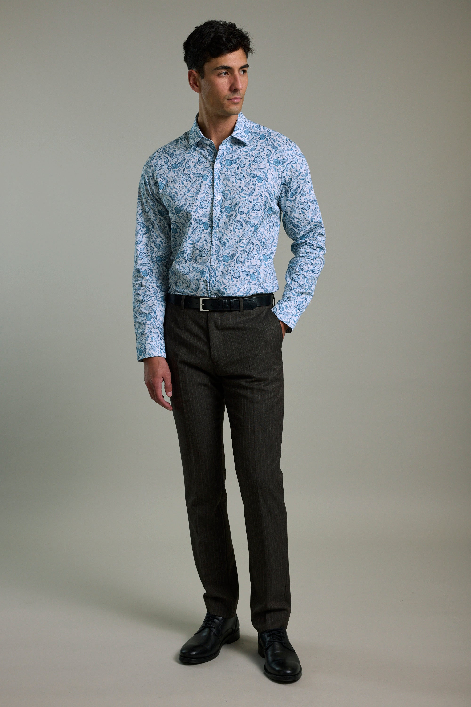 Man wears a Barkers Ronton Print Business Shirt, dark trousers, and black shoes in studio.
