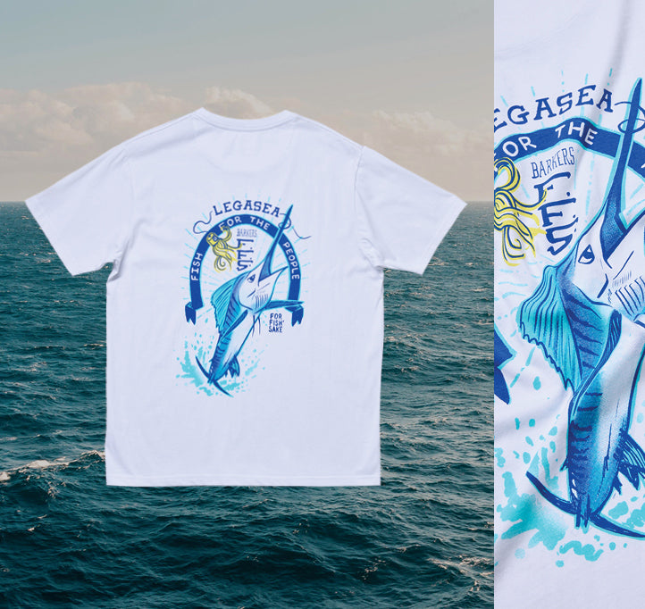 A white t-shirt featuring a graphic of a leaping marlin, water splashes, and the text “LEGASEA FOR THE FISH BARRIERS” on the back, displayed against an ocean background.