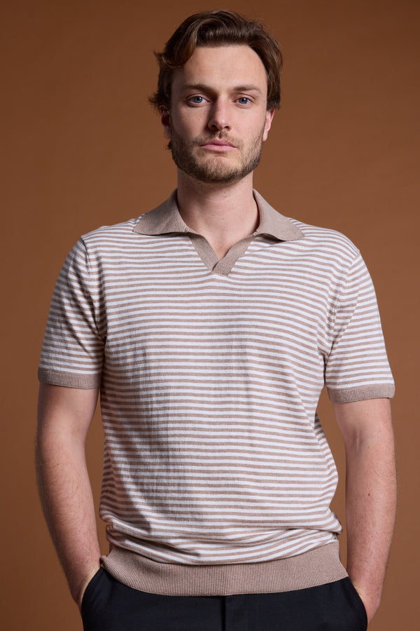 A man with light brown hair and a short beard stands against a brown background, wearing the Barkers Parkway Cotton Stripe Polo with a collar. His hands are in his pockets and he has a neutral expression.