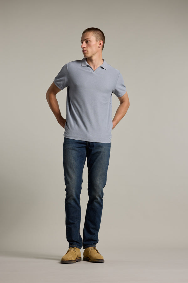 Man in a Barkers Winfield Textured Polo, jeans, and tan shoes stands against a plain background.