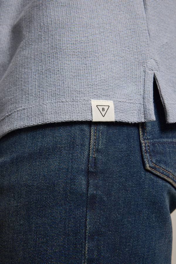Close-up of Barkers Winfield Textured Polo in light blue, styled with blue jeans.