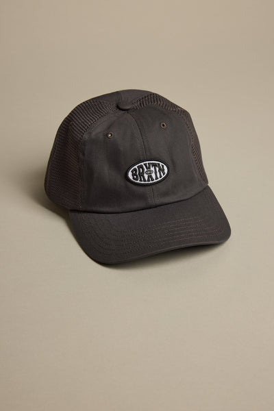 The Brixton Largo NP LP Snapback Cap by Brixton is a black mesh trucker hat with a curved brim, oval "BRAIN" patch, and eco-conscious Netplus design made from recycled fishing nets, shown on a beige surface.