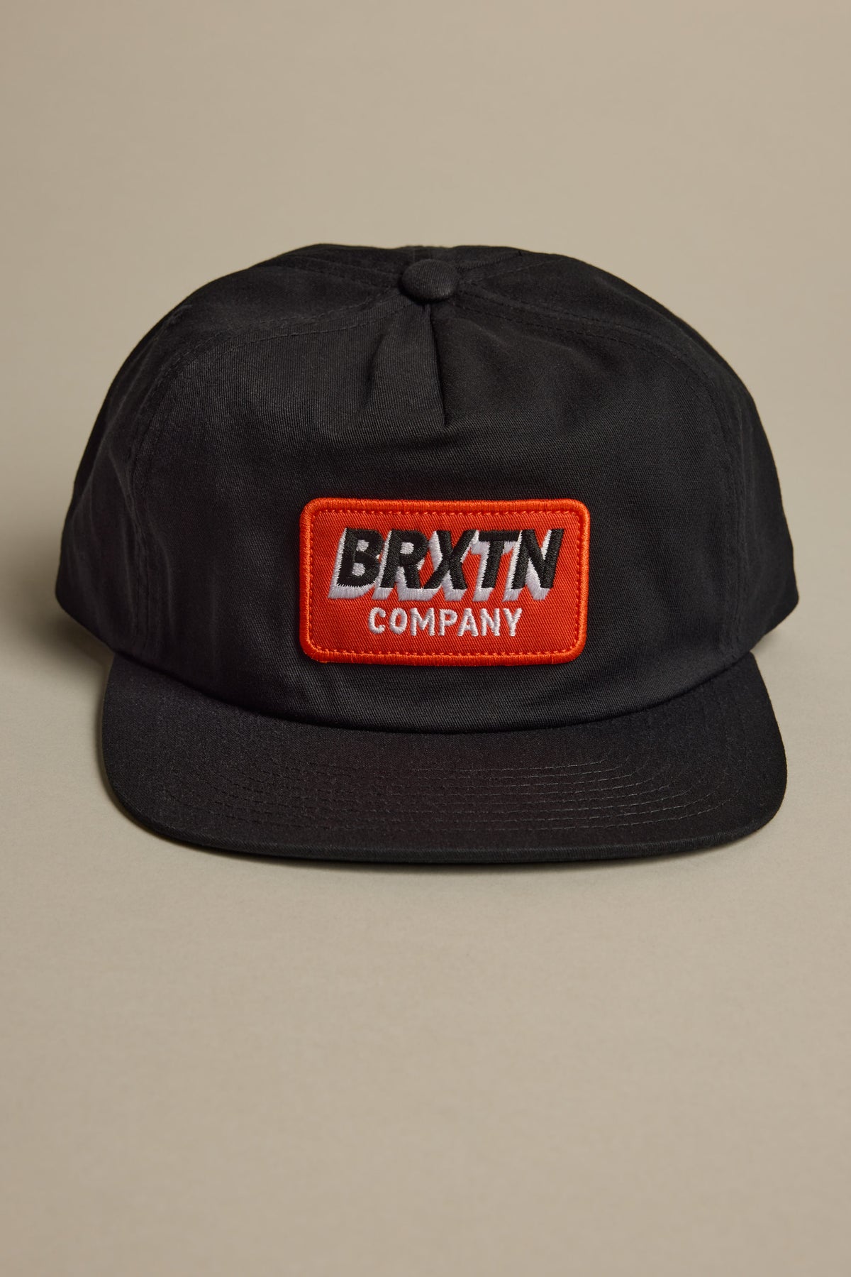 Black 5-panel Brixton Payment MP Snapback with red patch; adjustable closure.