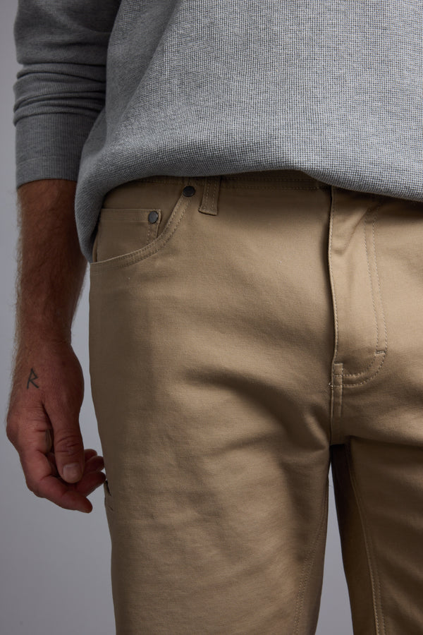 A person wears a light gray sweater tucked into beige Barkers Anvil 5Pkt Short with an elasticated waistband. Their left hand, featuring a small "R" tattoo, is visible. The photo is cropped at the chest and mid-thigh.