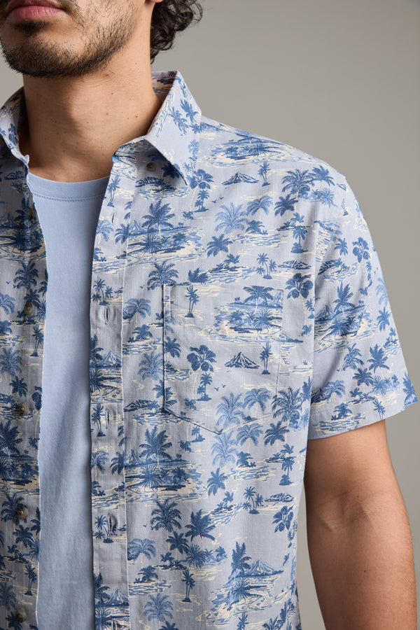 A person is wearing a Barkers Radford Print Shirt with a blue and white tropical palm tree pattern; only their lower face and upper body are visible.