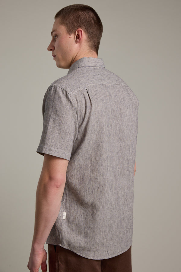 A person with short hair is seen from behind wearing a Barkers Woodley Texture Shirt and brown pants, standing against a plain light gray background.