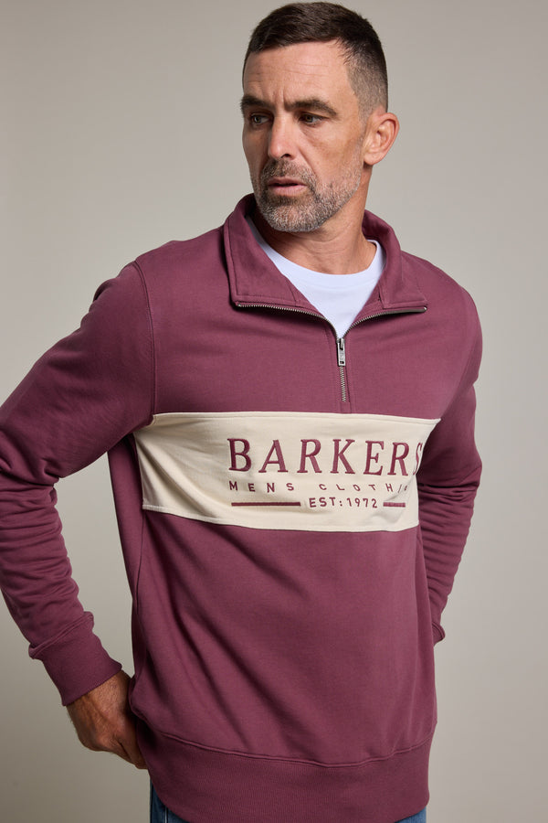 A man with short brown hair and a trimmed beard wears the Barkers Heritage 1/4 Zip sweater, featuring "Barkers Mens Clothing Est. 1972" on a beige chest stripe, against a plain light background.