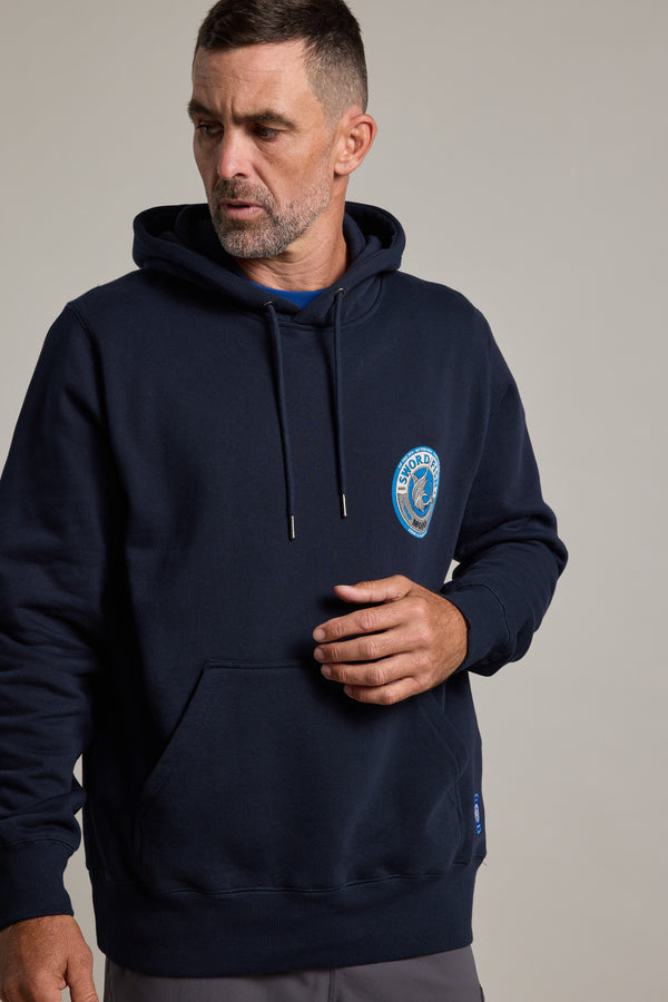 A man with short dark hair and a trimmed beard wears the Swordfish Mojo Logo Hoody by Swordfish Mojo, made from responsibly sourced cotton, featuring a small circular chest logo, as he looks to his left against a plain light background.