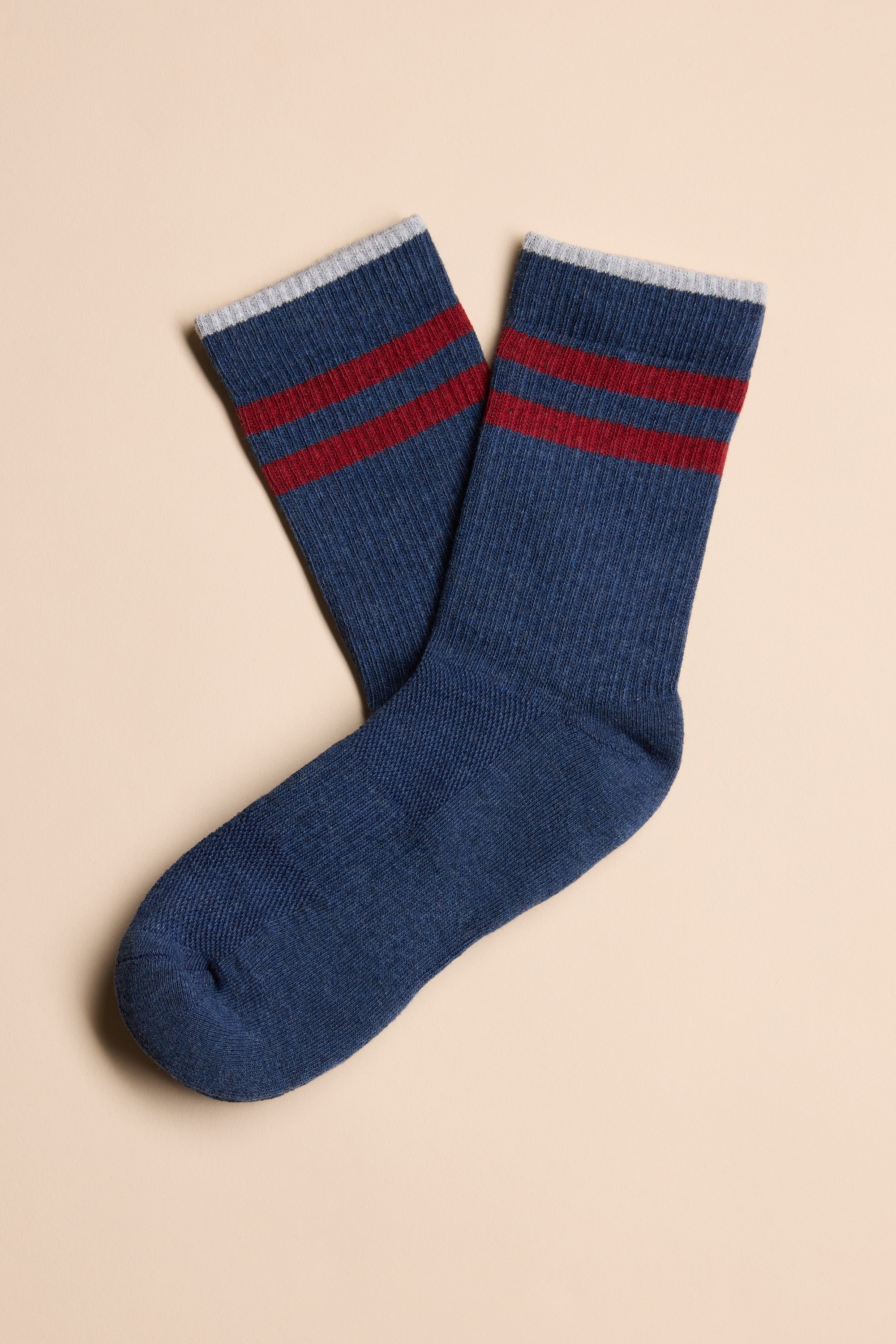 A pair of blue Barkers Emerson Sport Socks featuring two red stripes near the top and white cuffs, laid flat on a beige background.