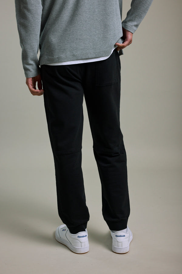 Person in Barkers Organic Classic Print Track Pant, gray sweater, and white Reebok sneakers, rear view.