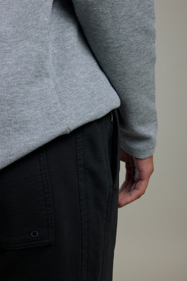 Person in a grey shirt and Barkers Organic Classic Print Track Pant, hand by their side.
