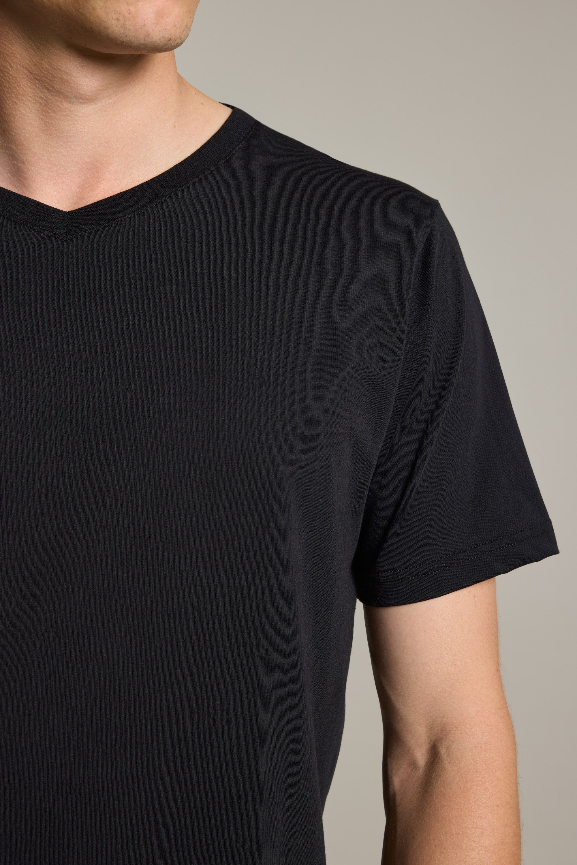 A person models the Barkers Organic Cotton V Neck Tee, shown from shoulders to mid-torso against a neutral backdrop. This mid-weight everyday staple appears with their face partially out of frame.