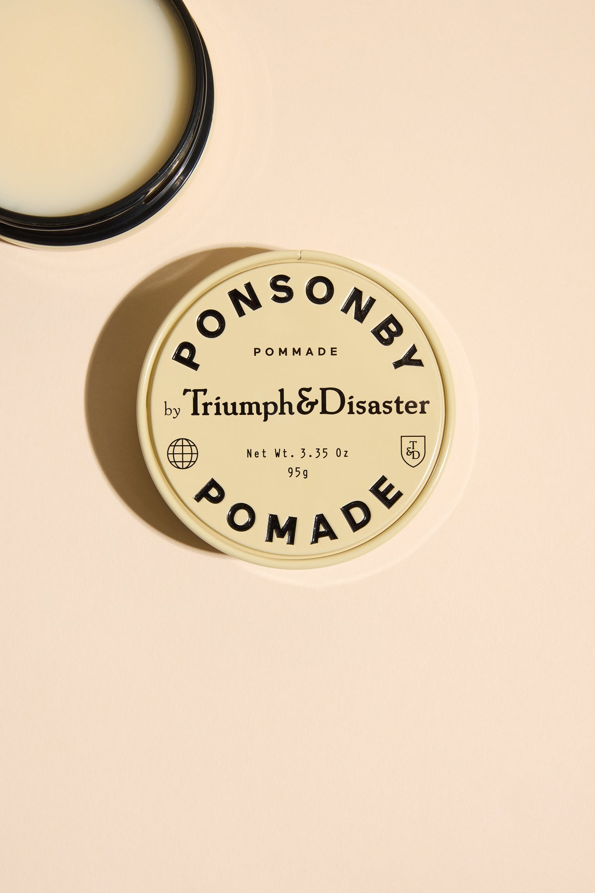 Triumph & Disaster Ponsonby Pomade tin with lid off, shown on beige background.