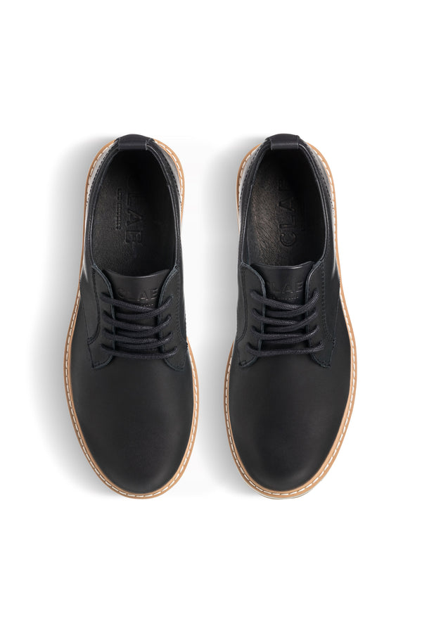 The CLAE Logan by Clae are black lace-up dress shoes with tan soles, made from premium leather and a recycled PU foam insole, shown from above on a white background.