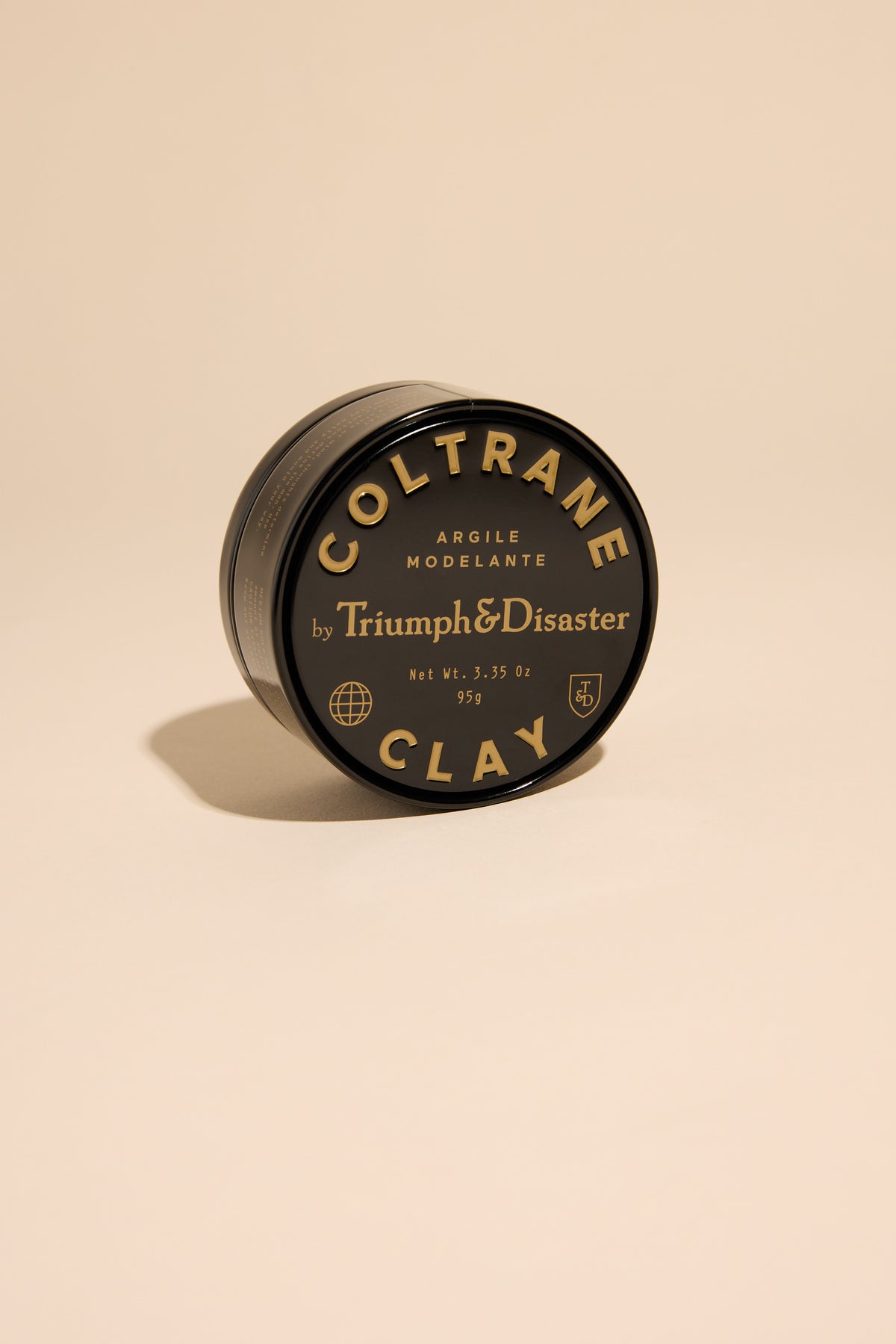 A black tin of Triumph & Disaster Coltrane Clay shown on a beige background.