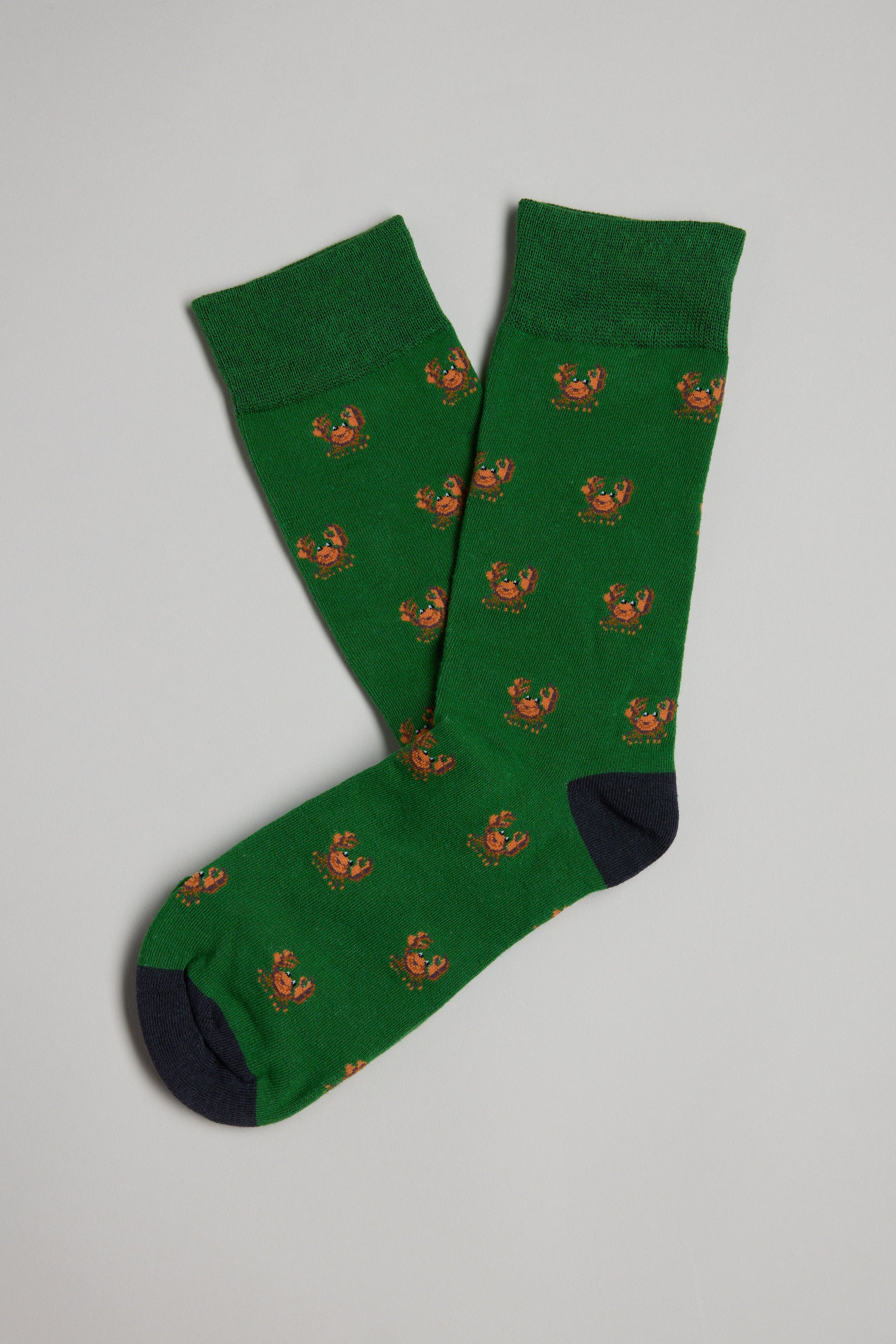 The Barkers Crab Sock is a pair of men's green cotton socks with small orange crab patterns and black toes and heels, shown flat on a light gray background—a fun, unique gift choice.