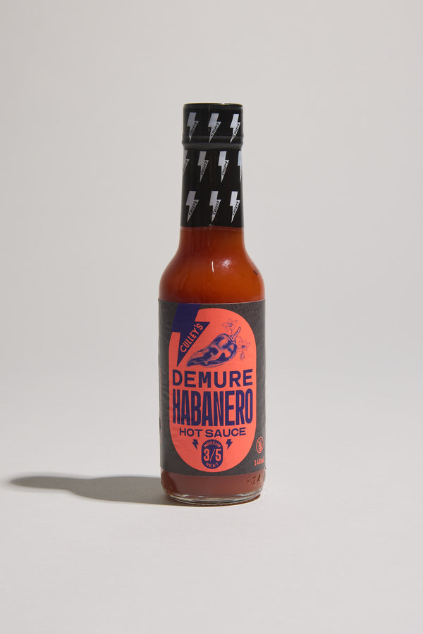 A bottle of Culley’s Demure Habanero Hot Sauce with a black and orange label.