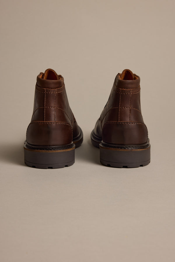 The Carlton Boot by Barkers—brown Italian leather ankle boots, shown from the back and side by side on a light beige surface—offers men a luxury footwear option.